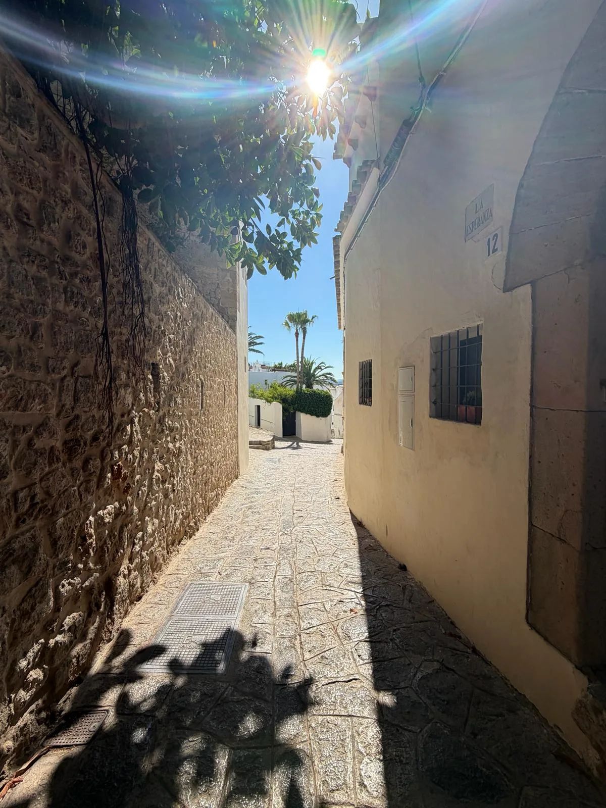 Carrer de la Esperança en Dalt Vila con paredes encaladas que descienden hacia una vista al mar