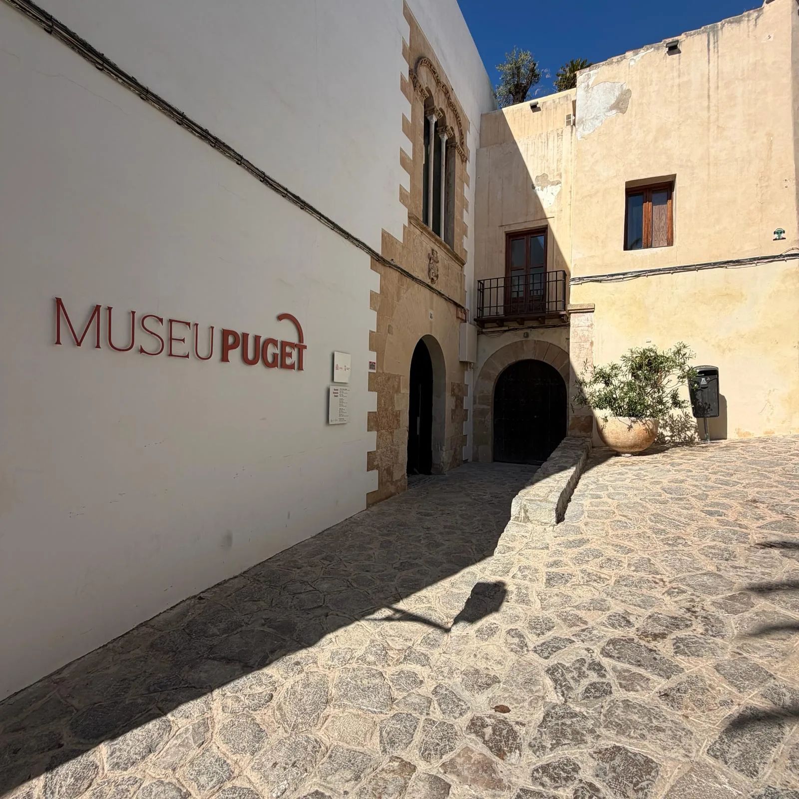 Puerta pintada de verde vibrante en un muro de piedra a lo largo de una calle empedrada en Dalt Vila