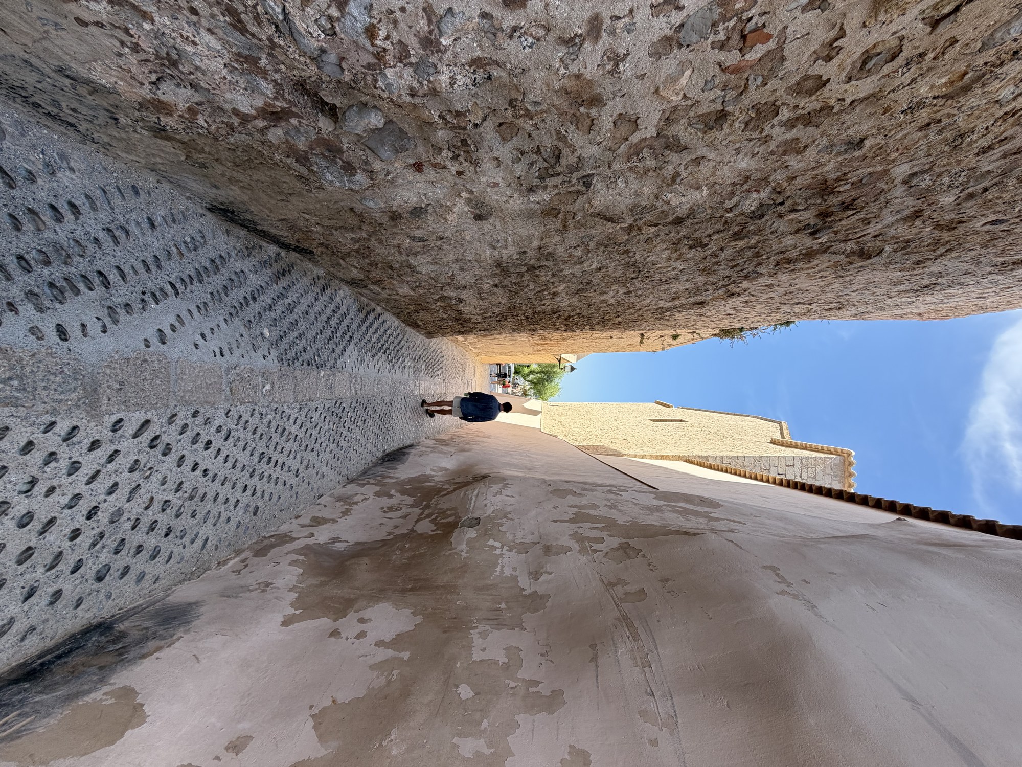 Callejón medieval empedrado flanqueado por las murallas de la fortaleza de Dalt Vila en Ibiza.