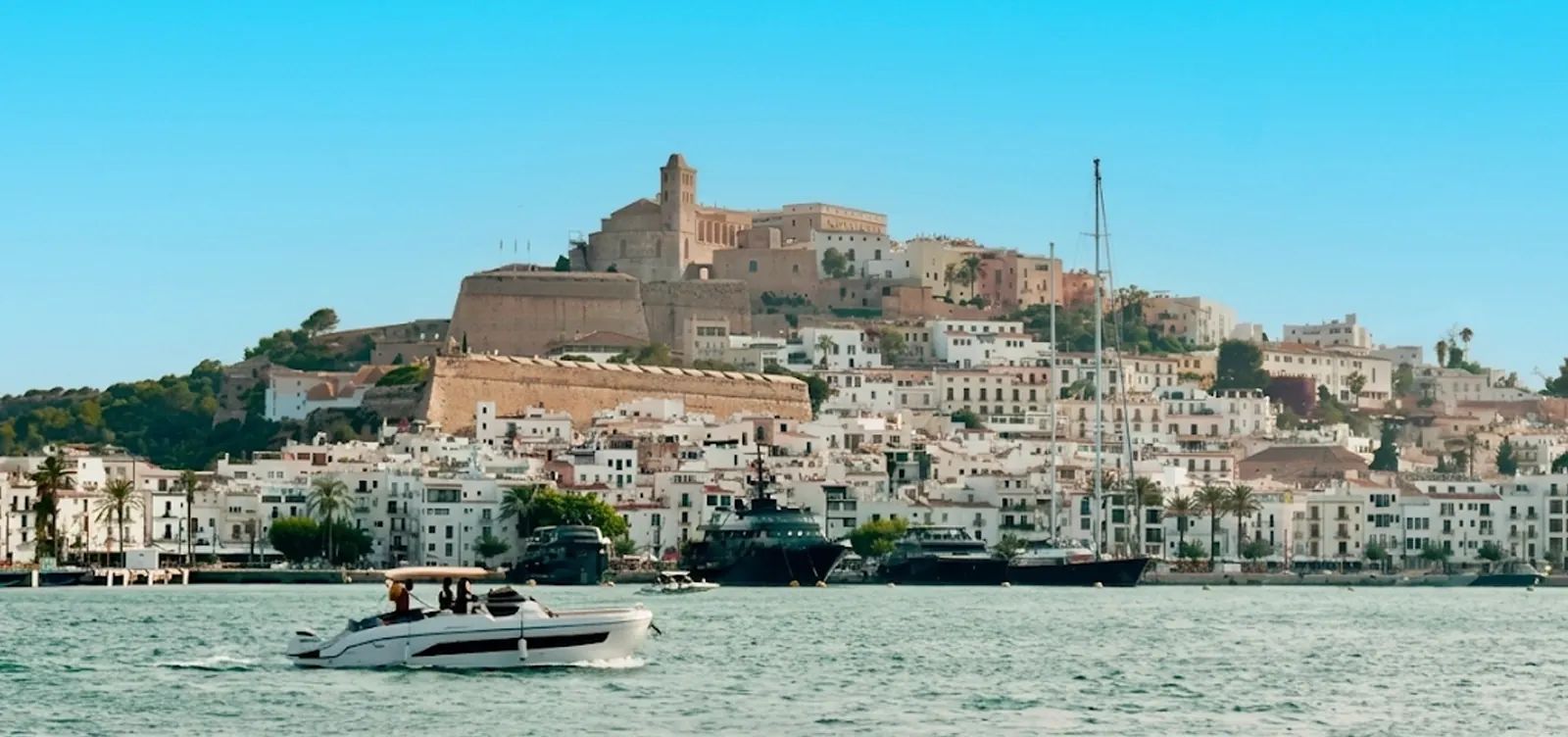 Dalt Vila's fortified old town and Ibiza Cathedral seen from the harbour, with a boat crossing the bay