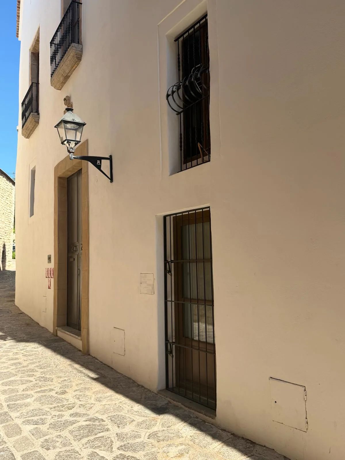 Farol de calle ornamentado montado en una fachada histórica en Dalt Vila, luz cálida de la tarde
